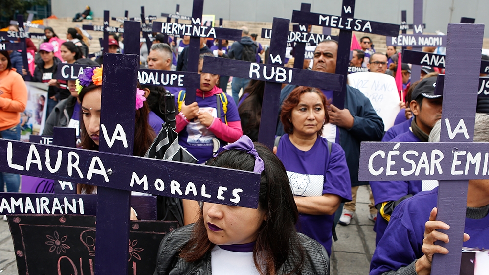 Activists hold crosses on the steps of the Angel of Independence Monument in memory of women who have been murdered or disappeared, to demand justice for their loved ones, one day after the Day of the