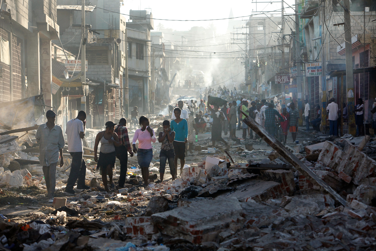 Haitians cover their faces to mask the smell of decaying bodies on a street in Port-au-Prince, Haiti, Saturday, Jan. 16, 2010. While workers are burying in mass graves some of the tens of thousand of