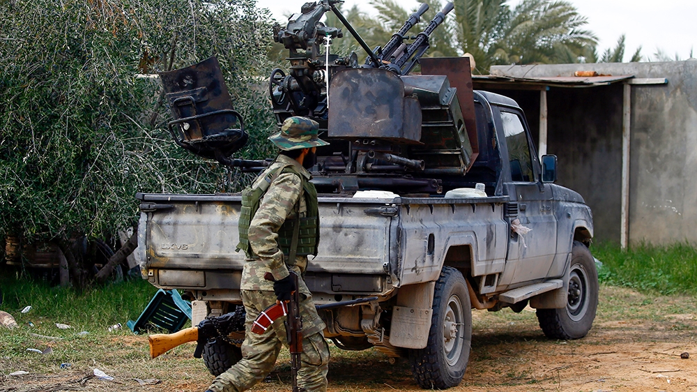A fighter loyal to the internationally recognised Libyan Government of National Accord (GNA) walks past a vehicle in an area south of the Libyan capital Tripoli on January 12, 2020. Both sides in Liby