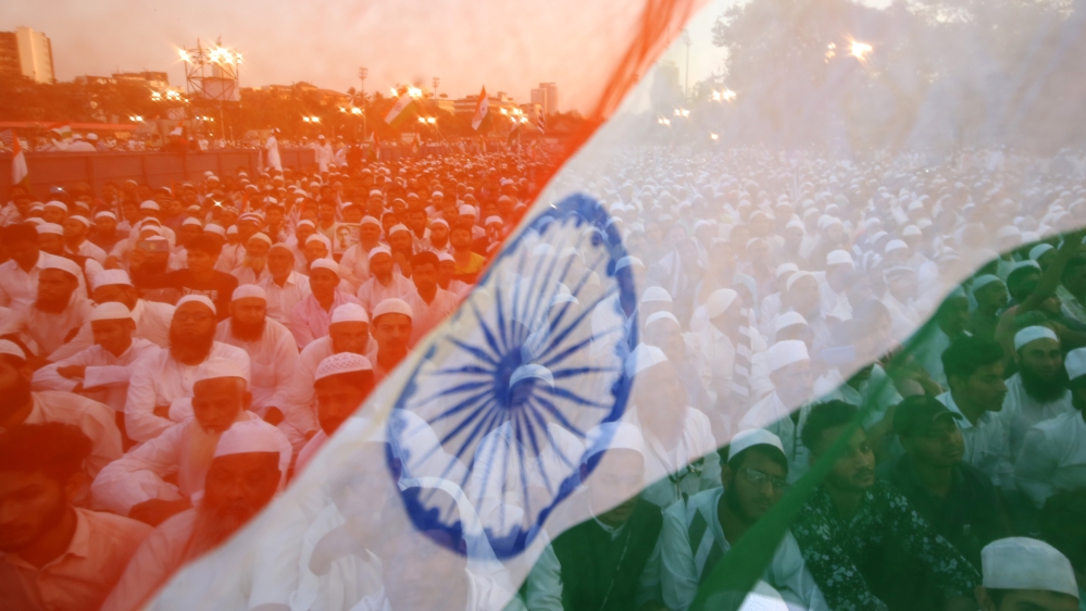 Demonstrators are seen through the Indian national flag as they attend a protest organised by Jamiat Ulama-i-Hind, a Muslim group, against a new citizenship law, in Mumbai