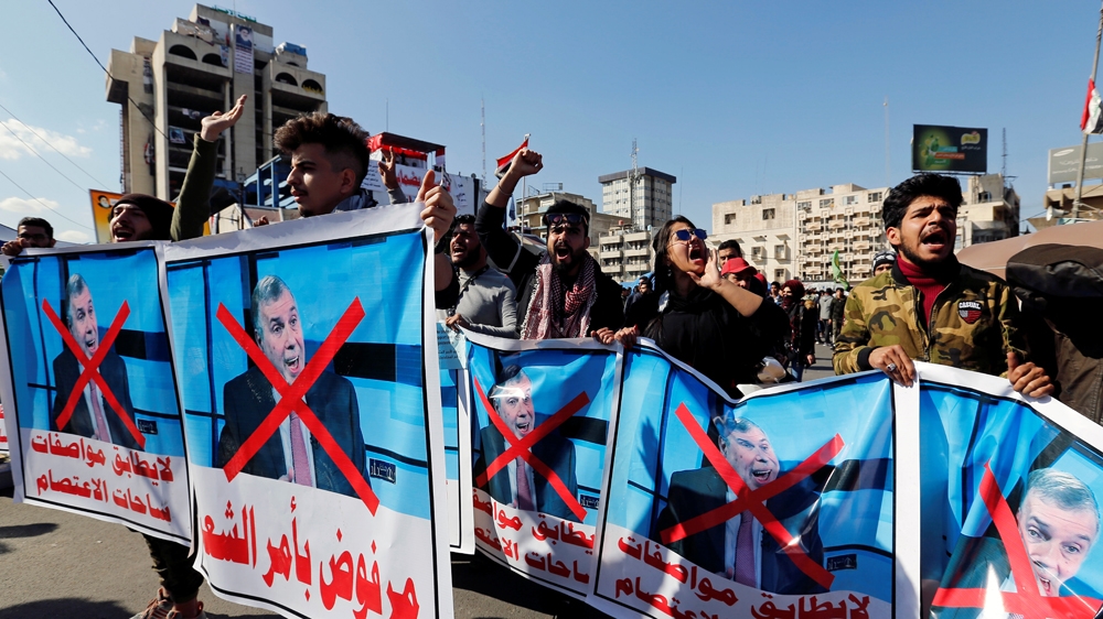 Iraqi demonstrators and university students carry posters depicting the newly appointed Prime Minister of Iraq, Mohammed Tawfiq Allawi, to express their rejection of him,