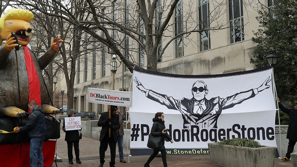An inflatable rat depicted as US President Donald Trump is seen outside federal court, next to a sign demanding a pardon for Stone