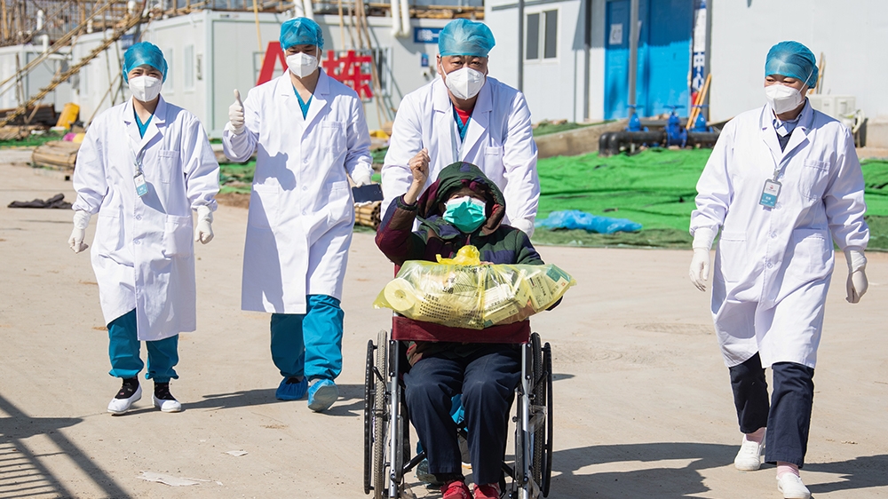 A recovered patient (C in wheelchair), 83, is discharged from Leishenshan Hospital, the newly-built makeshift hospital for novel coronavirus patients, in Wuhan in China's central Hubei province on Feb