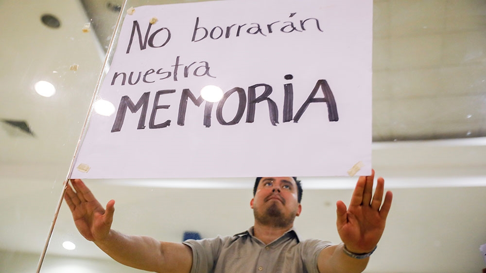 A human rights activist protests during a congress session over the law. The poster reads: ‘They won’t erase our memory’