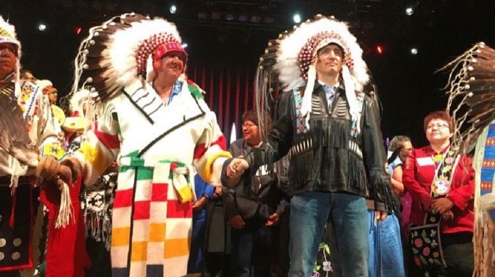 PM Trudeau holding the hand of TsuuT’ina Chief Roy Whitney after his honouring ceremony