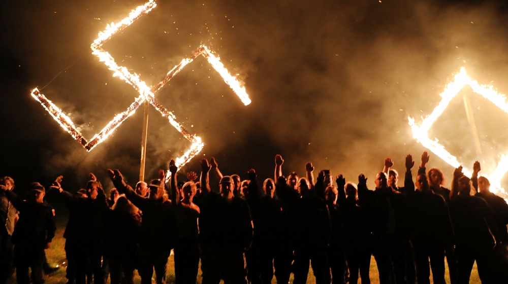Members of the National Socialist Movement, one of the largest neo-Nazi groups in the US, hold a swastika burning after a rally on April 21, 2018 in Draketown, Georgia. Community members had opposed t