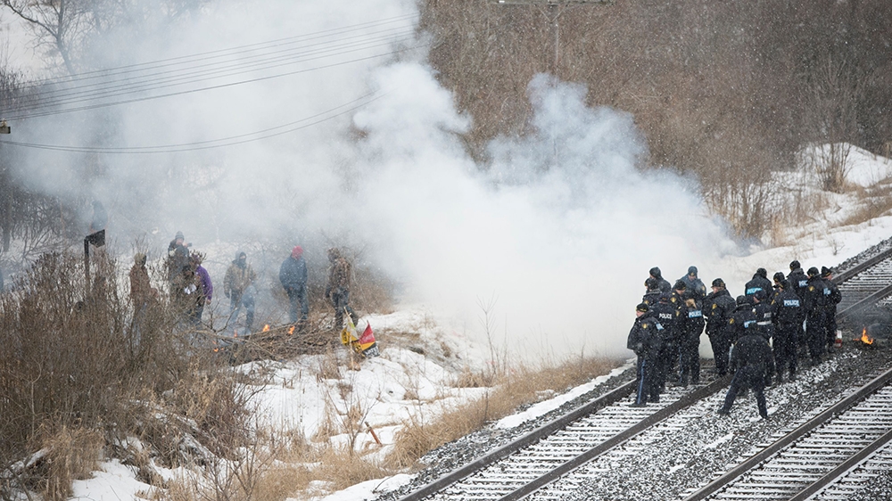 OPP officers douse flames lit on Canadian National Railway (CN Rail) tracks beside an encampment of the Tyendinaga Mohawk Territory, set up in support of the Wet'suwet'en Nation who are trying to stop