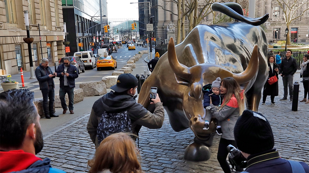 People pose for photos with the Charging Bull statue in New York’s Financial District, Sunday, March 15, 2020. New York Gov. Andrew Cuomo Cuomo said Saturday that more than 600 New Yorkers have been d