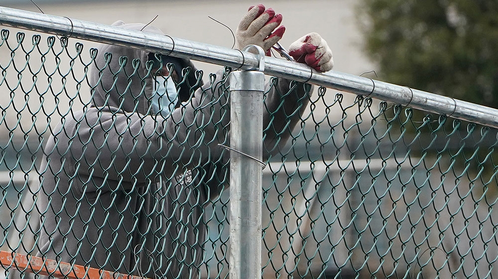 Workers stand near a fence during the outbreak of COVID-19 in the Manhattan borough of New York City