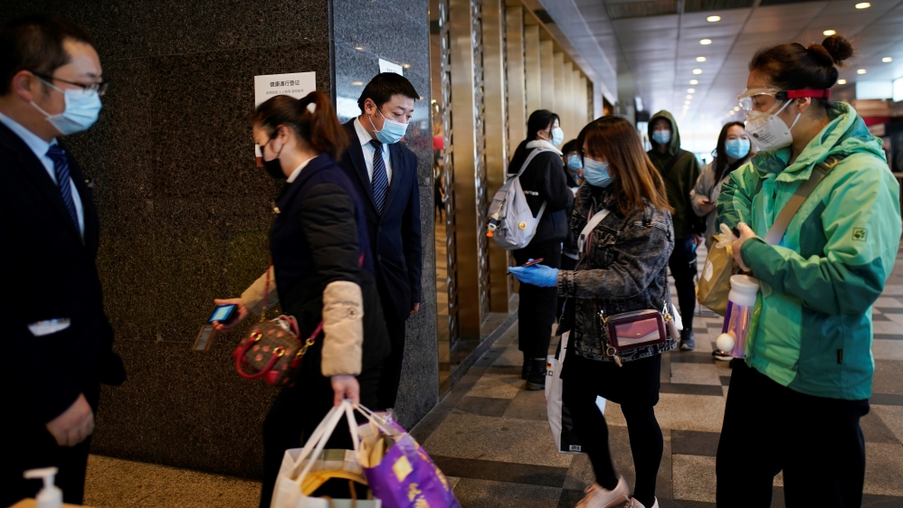 Management staff check QR codes on the mobile phones of people entering a shopping mall at its entrance in Wuhan