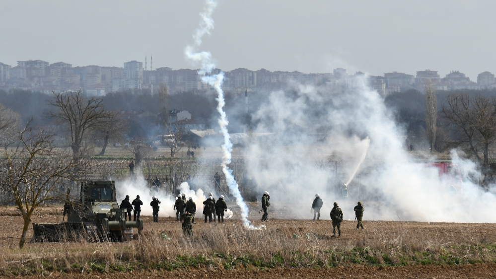 Greek riot police officers stand guard as tear gas is being fired near Turkey''s Pazarkule border crossing, in Kastanies