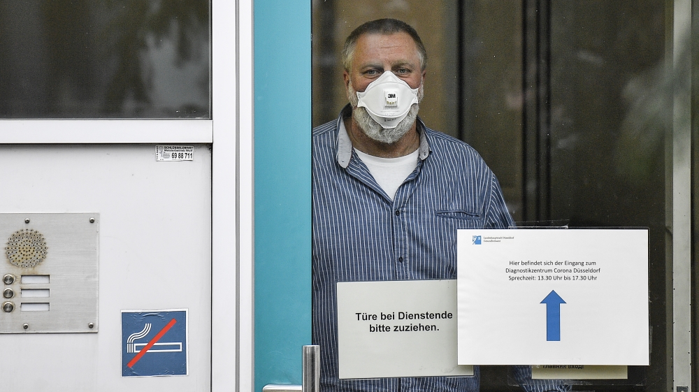 An employee with face mask and gloves waits behind the door of the corona diagnostic center in Duesseldorf, Germany, Monday, March 2, 2020 for the next patient. Germany faces several people infected w