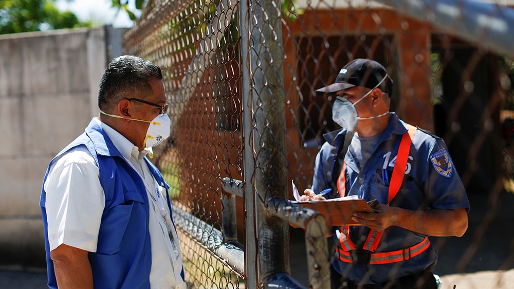 A representative of the Office of the Prosecutor for the Defence of Human Rights talks to a security guard at a facility where travellers are in quarantine as El Salvador enforces measures due to coronavirus disease (COVID-19) concerns, in Tierra Blanca, El Salvador