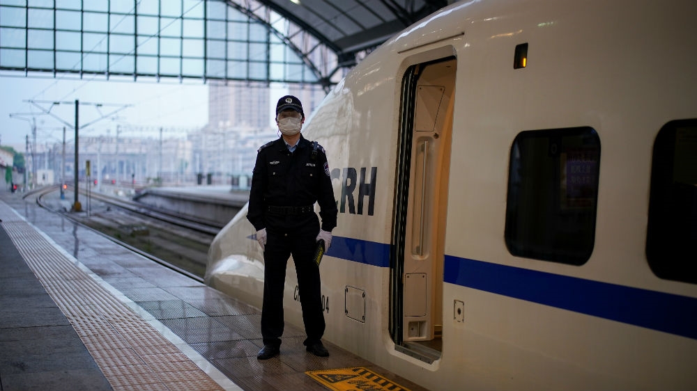 A policeman stands beside a high-speed train – the first to leave Wuhan’s Hankou Railway Station in two months