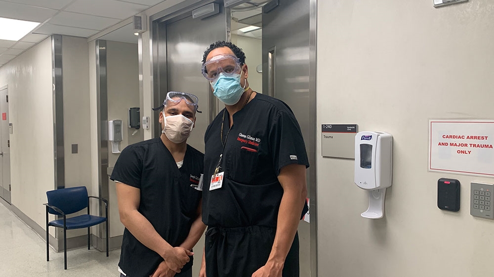 Gilman and a colleague in the hallway of a hospital where they battle COVID-19 together [Courtesy of Dr Cleavon Gilman]