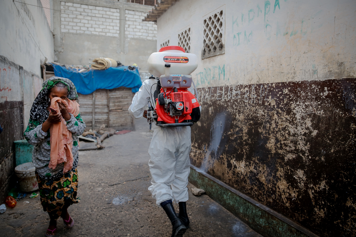 A woman hurries out of a daara or Qur’anic school for children as municipality workers arrive to sanitize the building. Authorities have called upon Qur’anic school teachers to reinforce hygiene and s
