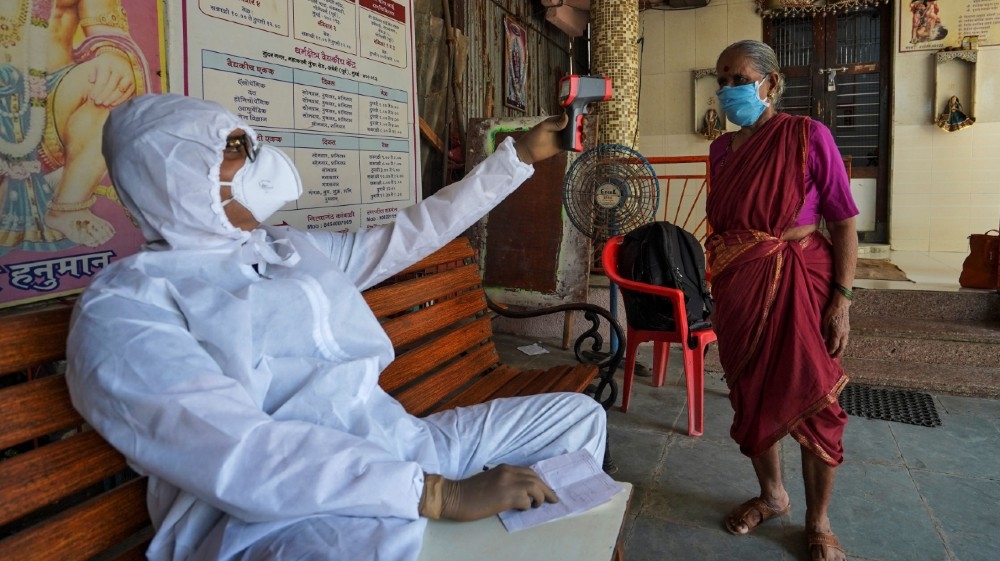 A doctor checks the temperature of a woman in a temporary health centre where he coaches slum dwellers on the precautions they should take to avoid being infected with the coronavirus in Mumbai, India