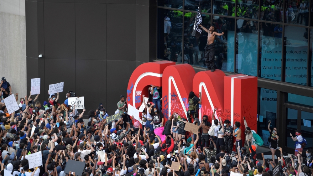 Demonstrators paint on the CNN logo during a protest in Atlanta