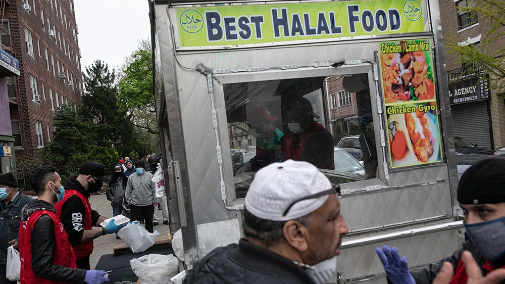 People queue up for free food handed out by volunteers from Muslims Giving Back, in red vests, in the Bay Ridge neighbourhood of Brooklyn