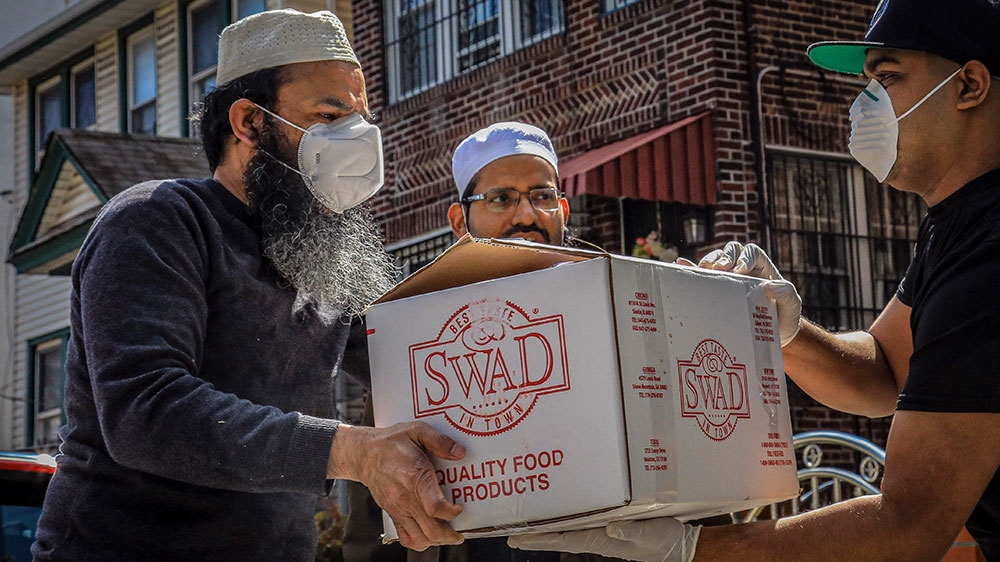 Imam Mufti Mohammed Ismail, centre, and volunteer Mohammad Q Ullah, left, delivers a box of food supplies prepared at An-Noor Cultural Center and masjid for those impacted by COVID-19 restrictions