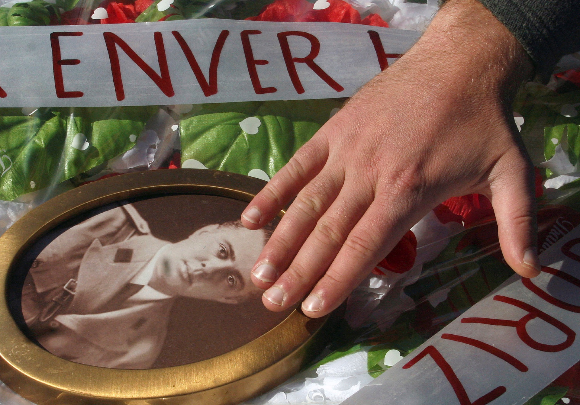 A communist supporter touches a photo of Enver Hoxha in Tirana