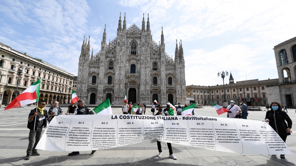 People wearing protective masks protest against the economic consequences of the lockdown at the Duomo square, as Italy begins a staged end to a nationwide lockdown, in Milan