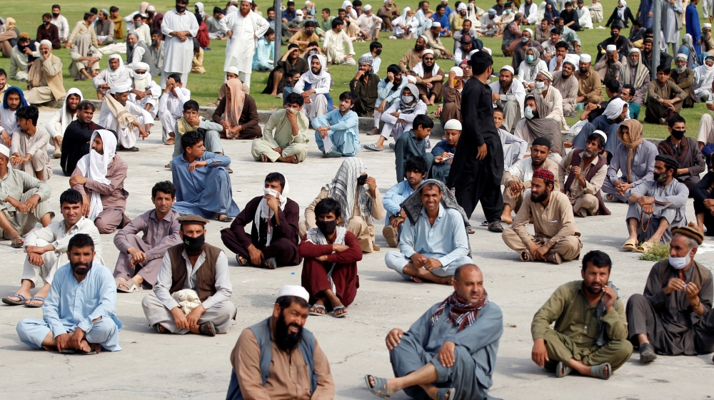 Men wait to receive free food donated by the Afghan government, amid the spread of the COVID-19 in Jalalabad