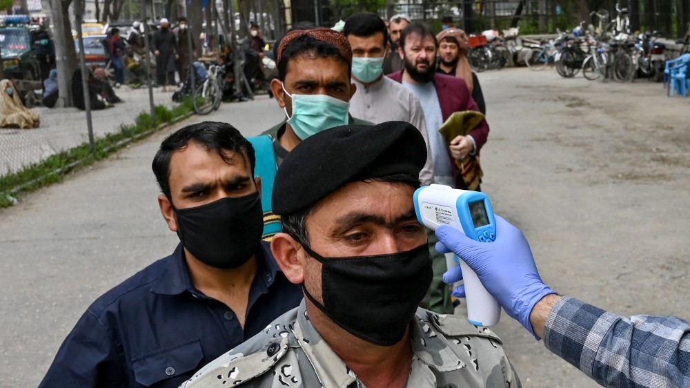 A health worker checks the body temperature of a devotee as a preventive measure against the COVID-19 coronavirus before the Friday prayers in