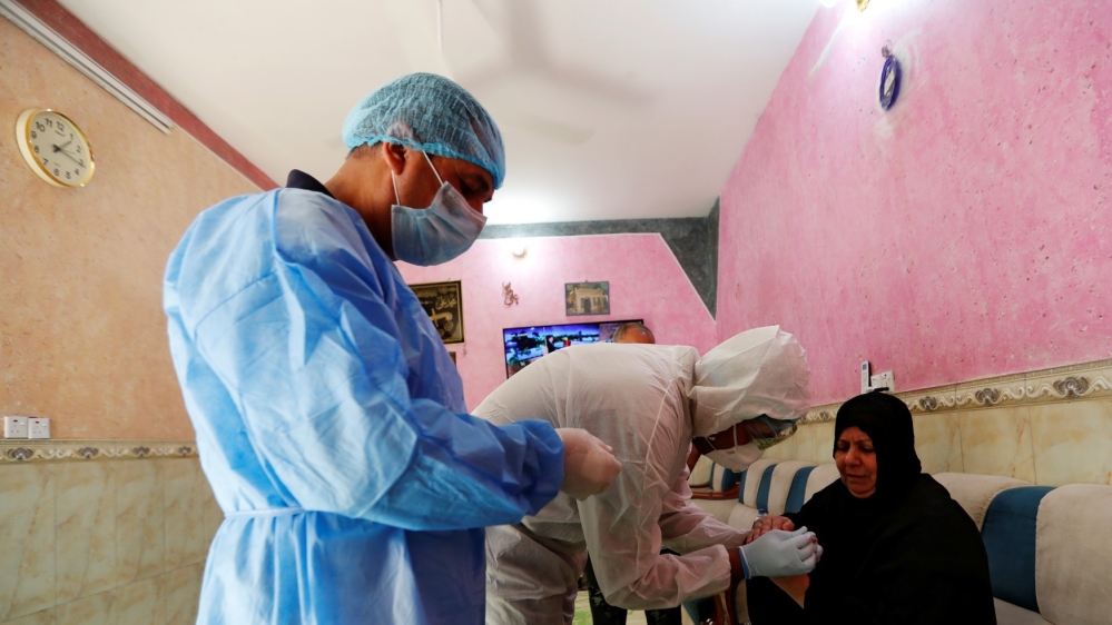 A healthcare worker takes blood samples from a woman during testing for the coronavirus in Sadr city, district of Baghdad, Iraq