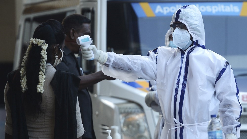 A health official checks the body temperature of passengers as they arrive to board a special train to New Delhi in Chennai on May 15, 2020