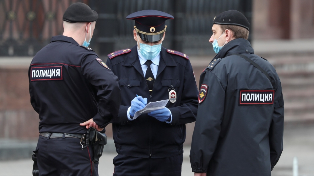 Police officers wearing protective face masks speak in a street amid the outbreak of the coronavirus disease in Moscow