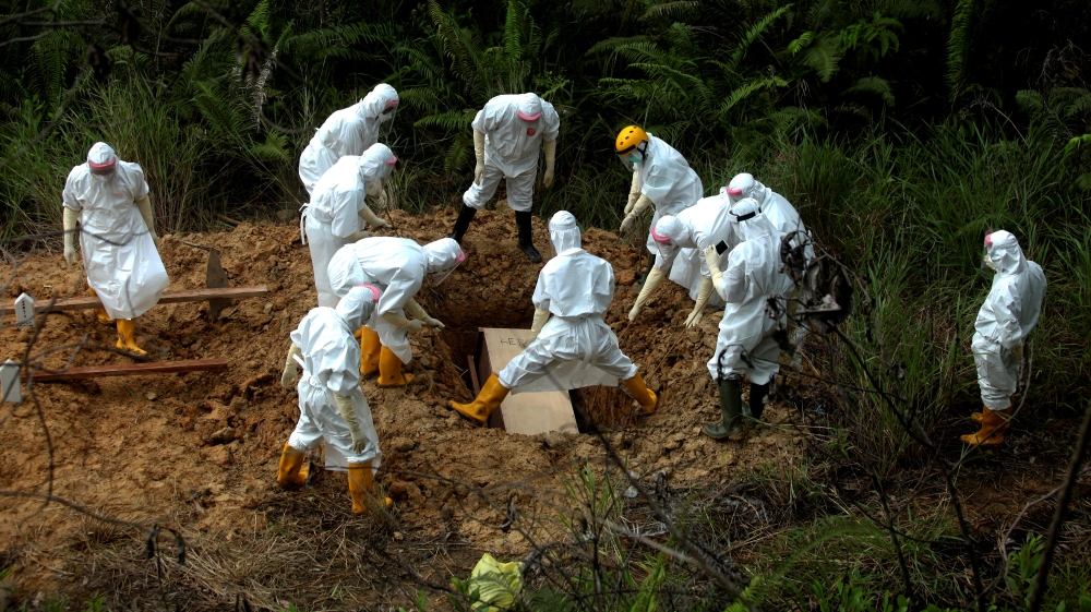 Municipality workers wearing protective gear bury a victim of the coronavirus disease (COVID-19) at a cemetery area provided by the government