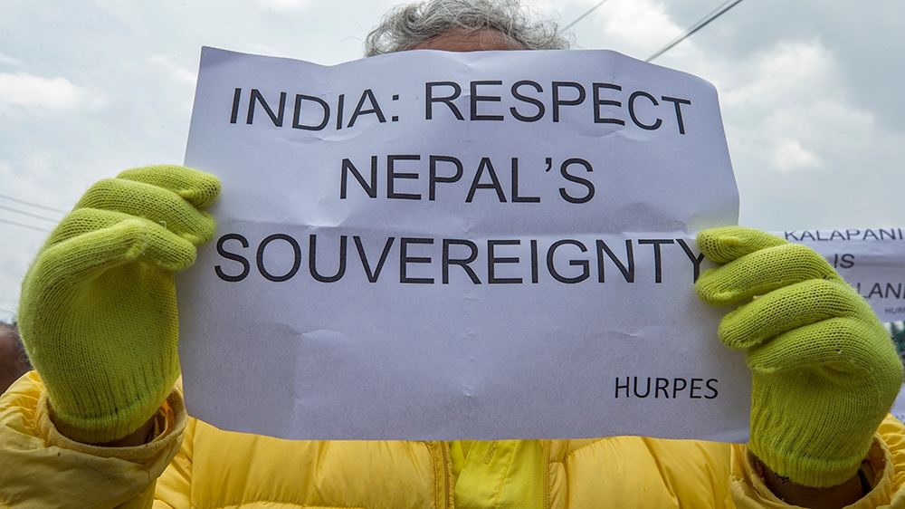 An activist affiliated with Human Rights and Peace Society Nepal holds a sign during an anti-Indian-government protest at the Indian Embassy in Kathmandu