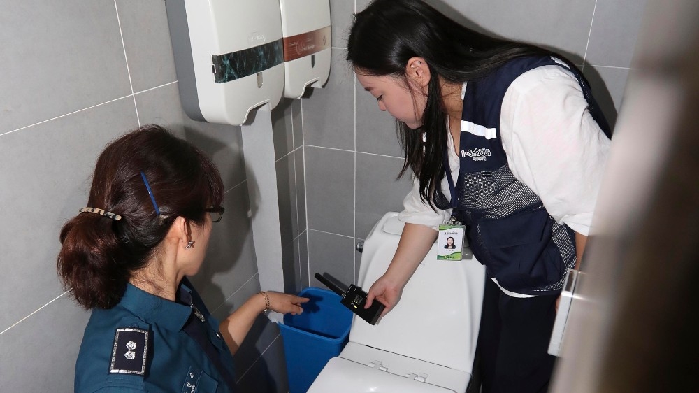 Police officers check a women’s restroom in Seoul as part of a campaign to root out sex crimes making use of hidden cameras {file: Yonhap via EPA]