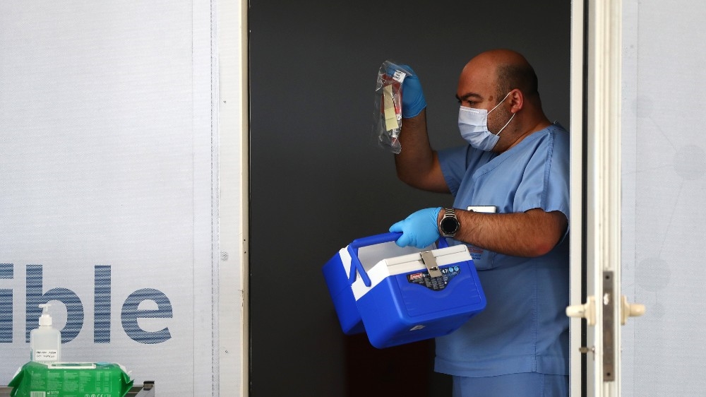 A medical worker, wearing a protective face mask and disposable gloves, collects swab tests in Abu Dhabi