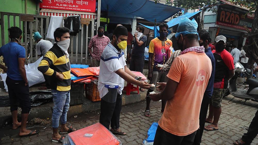 People buy tarpaulins from a roadside vendor in Mumbai as more states open up and crowds of commuters trickle on to roads in many of India’s cities
