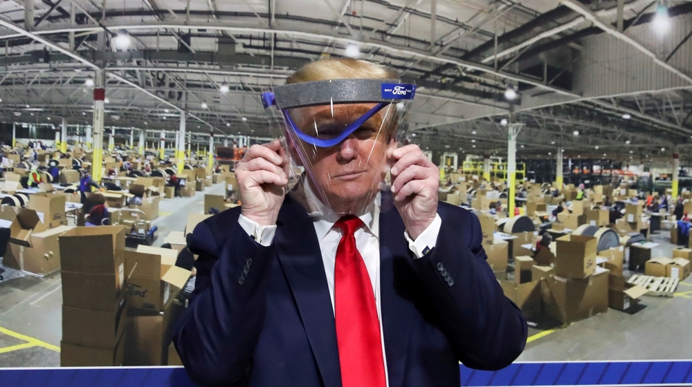 U.S. President Donald Trump holds up a protective face shield during a tour of the Ford Rawsonville Components Plant that is manufacturing ventilators, masks and other medical supplies during the coro