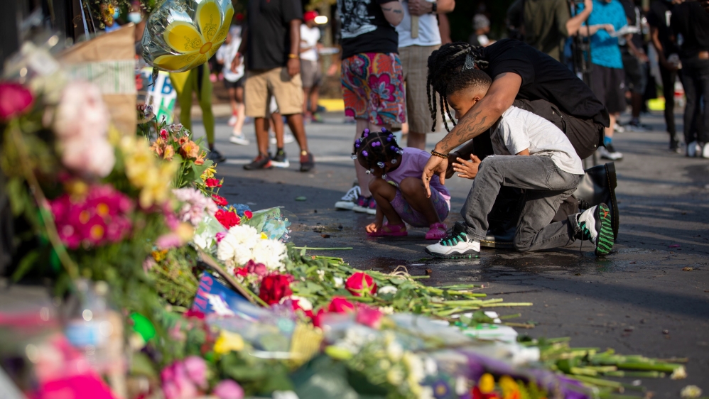 A man and two children mourn at the site of a Wendy’s restaurant where Rayshard Brooks, 27, was shot and killed by police in a struggle following a field sobriety test