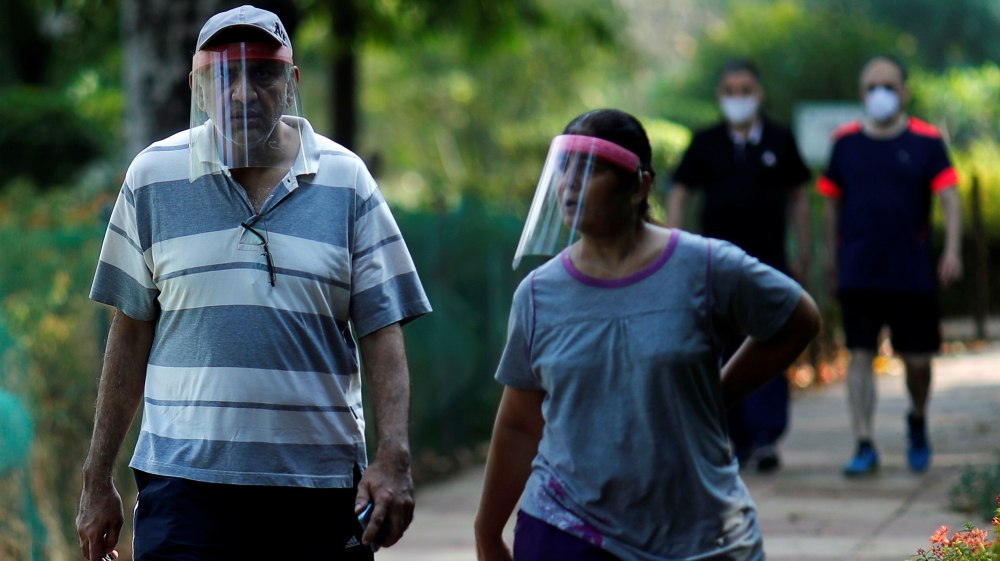 People wearing protective face shields walk inside a park after few restrictions were lifted, during an extended nationwide lockdown to slow the spread of the coronavirus disease in New Delhi
