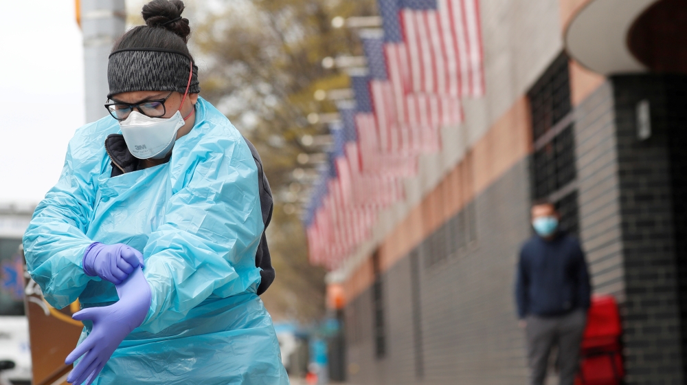 An Emergency Medical Technician (EMT) dons personal protective equipment before going into Elmhurst Hospital during the ongoing outbreak of the coronavirus disease (COVID-19) in the Queens borough of 