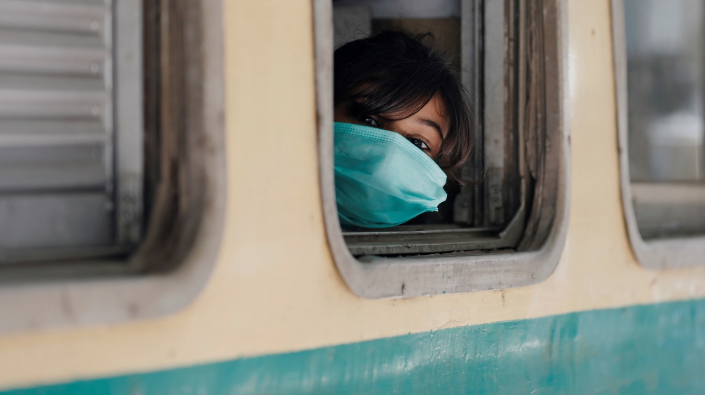 A girl wearing a protective mask looks out from a train window after Pakistan started easing the lockdown restrictions and allowed to resume passenger trains, following the COVID-19 outbreak, in Karachi