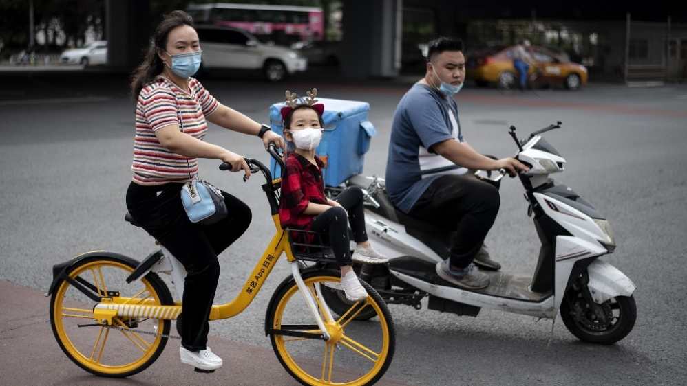People wearing face masks cross a street in Beijing on June 1, 2020