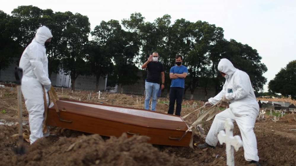 Brothers Carlos Alexandre and Wagner Cardninot, attend the burial on Saturday of their father, 76- year-old Jose Herminio de Farias, who died from COVID-19 in Rio de Janeiro, Brazil