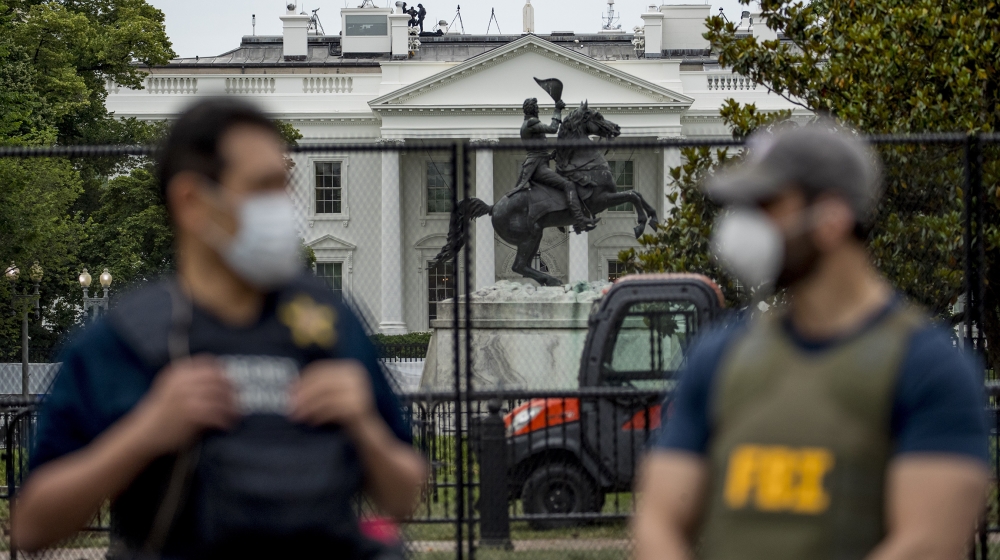 The White House is visible behind a large security fence as uniformed Secret Service and FBI agents stand on the street in front of Lafayette Park in the morning hours in Washington, Tuesday, June 2,