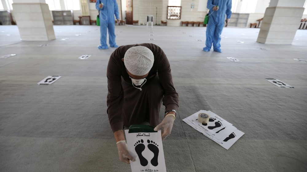 The Imam of a mosques puts foot print mats for social distancing to prevent the spread of the coronavirus in Amman, Jordan