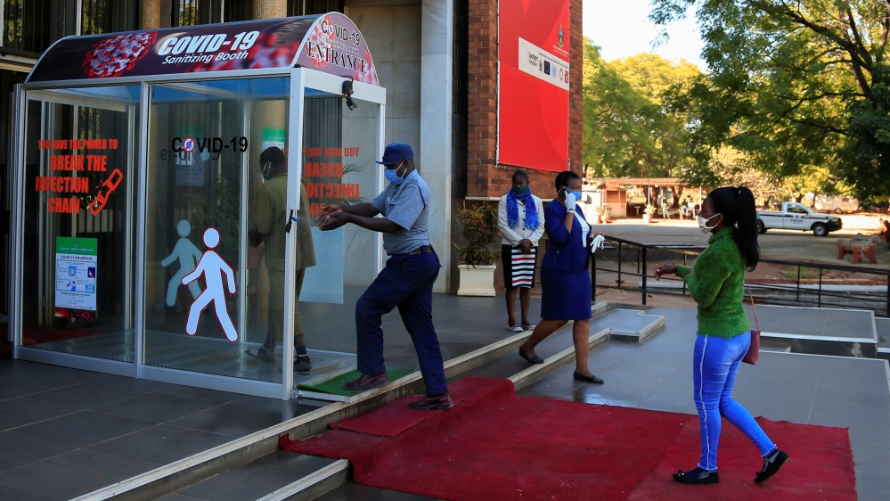 A policeman washes his hands as he enters a sanitizing booth during a nationwide lockdown to help curb the spread of the coronavirus disease (COVID-19) at a court in Harare, Zimbabwe