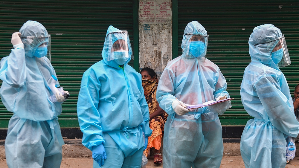 Residents watch as medical staff along with Hindu hardline group Rashtriya Swayamsevak Sangh (RSS) volunteers wearing Personal Protective Equipment (PPE) gear wait to start a door-to-door medical scre