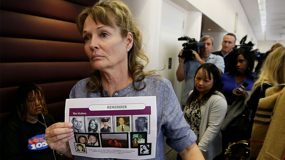 Melanie Barbeau displays photos of murder victims believed to be slain by the Golden State Killer as she leaves a hearing for suspect Joseph DeAngelo in Sacramento, California in 2018
