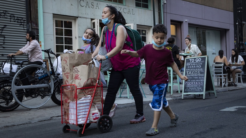 Pedestrians pass customers dining outside Casa Mezcal, Monday, June 22, 2020, in New York. New York City ventured into a crucial stage of reopening as stores let people in Monday, offices brought work