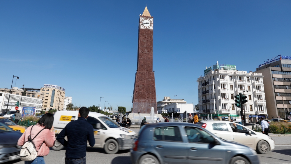Cars and people pass by the clock tower at the end of Avenue Habib Bourguiba in Tunis